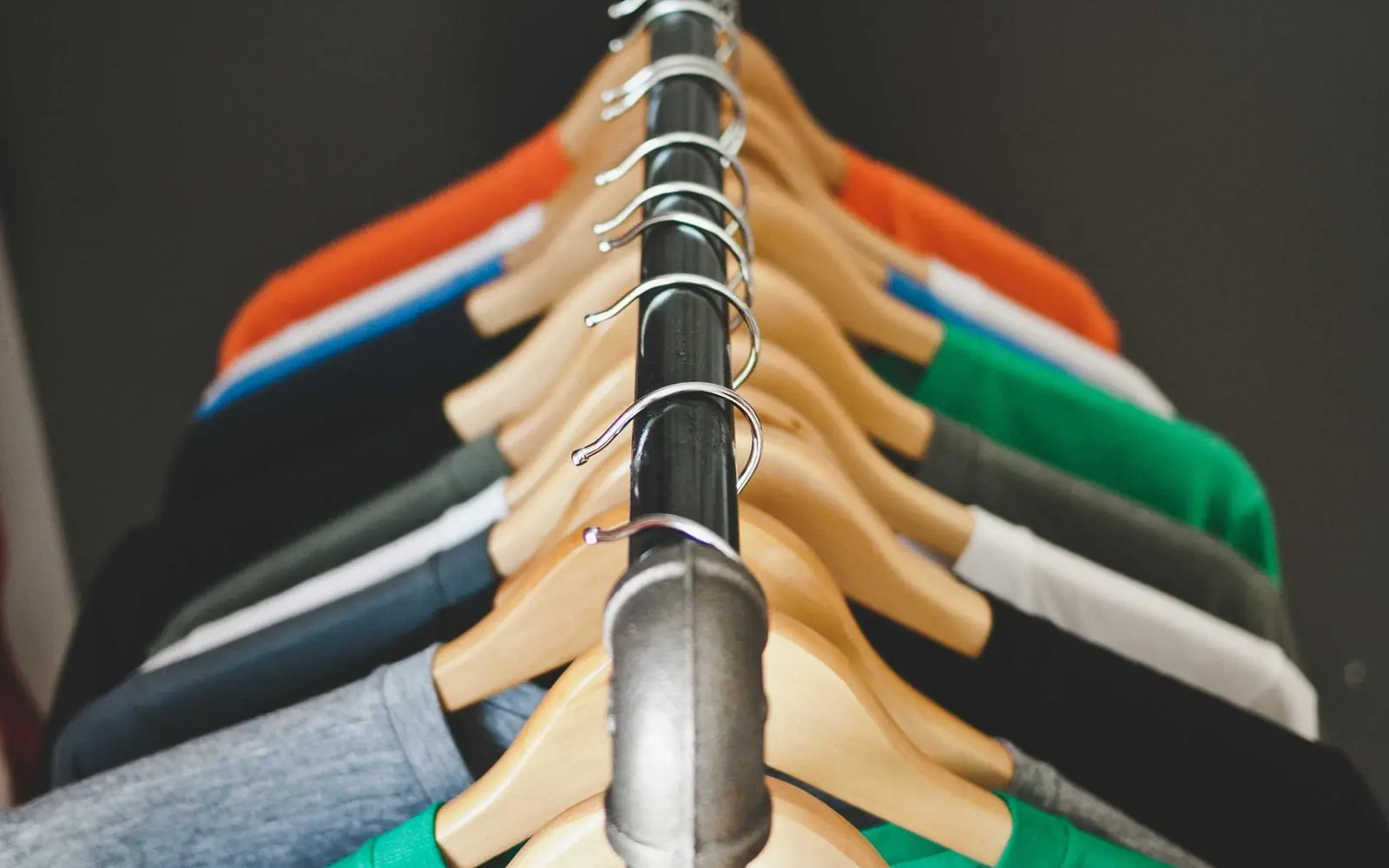 Colourful garments hanging on wooden hangers