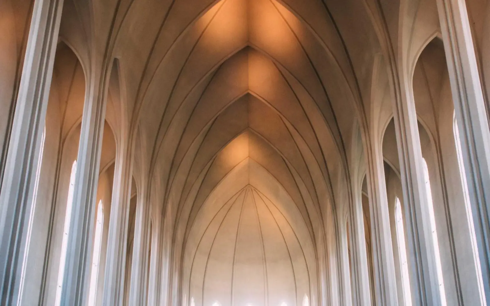 Tall pointed wooden arches leading toward bright light