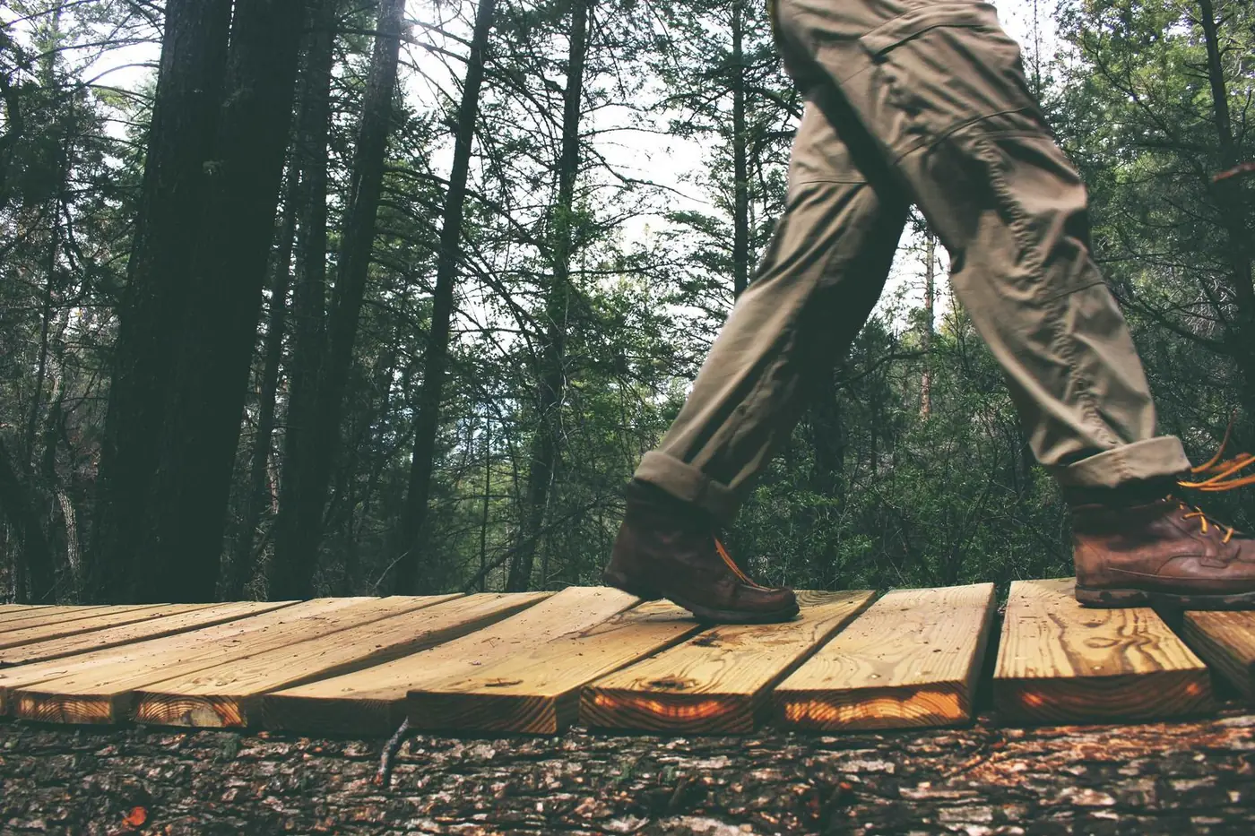 Hiking boots stepping along a wooden boardwalk in the woods
