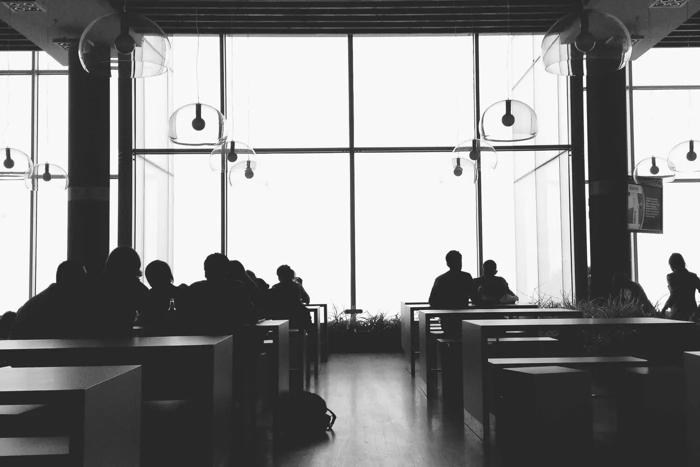 Silhouettes of people in a meeting room in front of large windows
