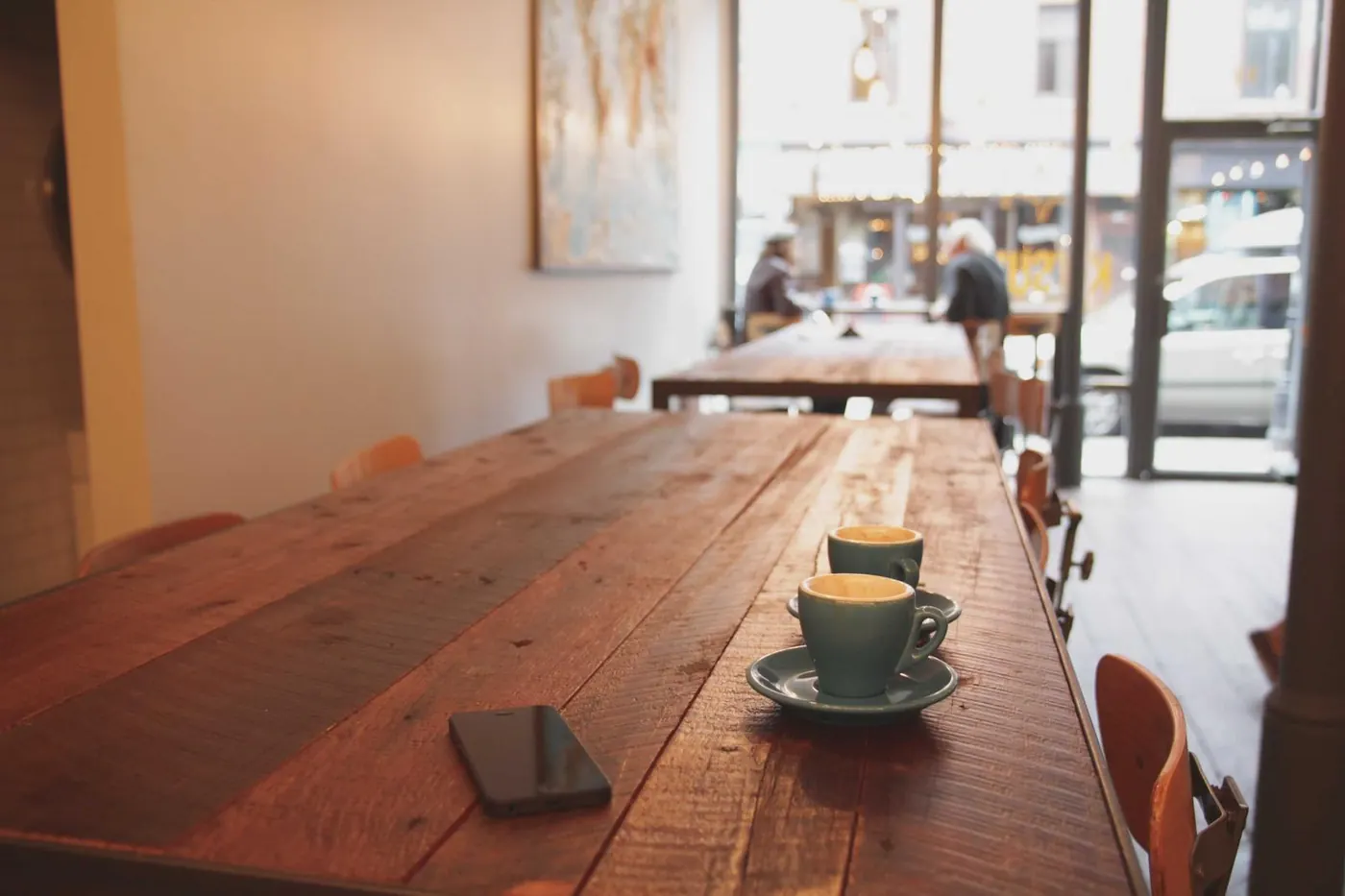 Bright café interior with a long wooden table and pendant lights