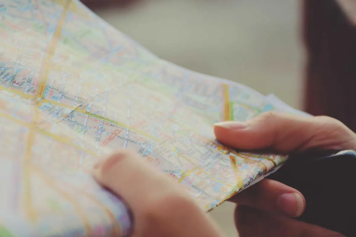 Hands unfolding a paper map outdoors